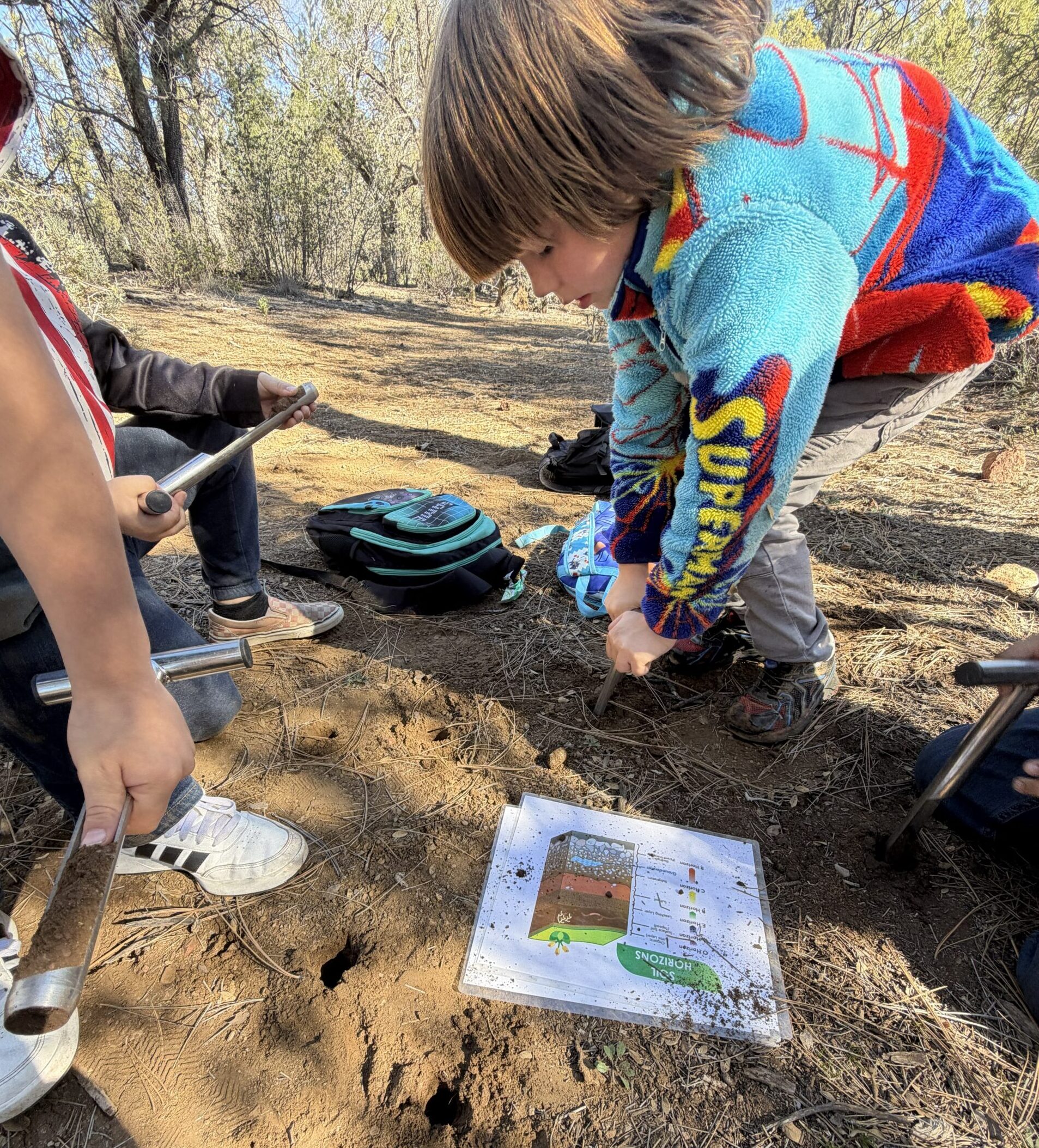 Child using soil auger to measure and identify soil layers.